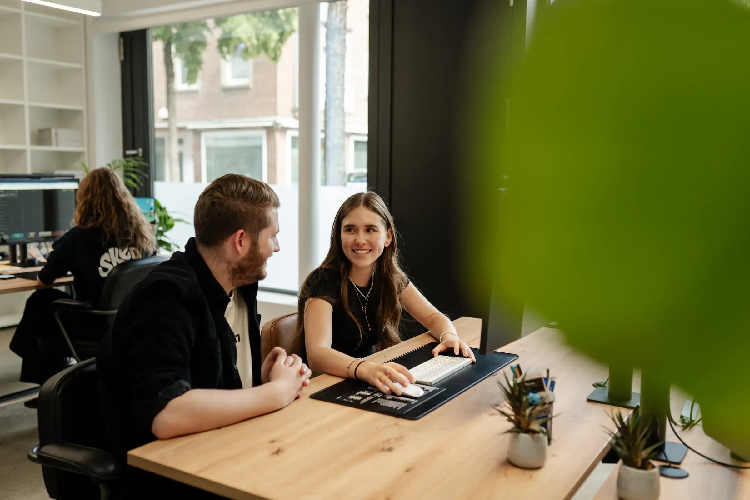 Zwei Teammitglieder von skeon digital am Tisch mit Laptop im Gespräch