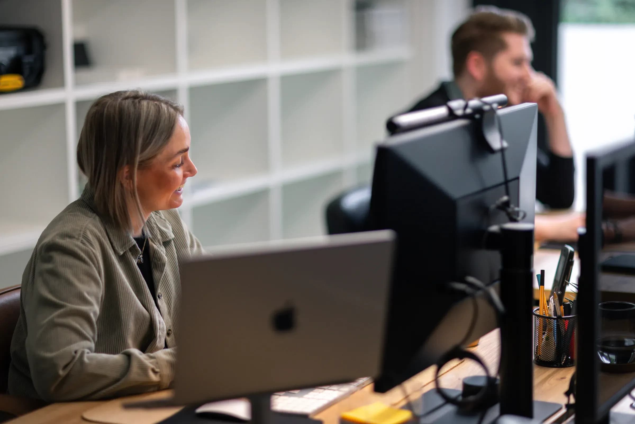 Kollegin von skeon digital am Monitor, im Hintergrund ein Kollege am Arbeitsplatz