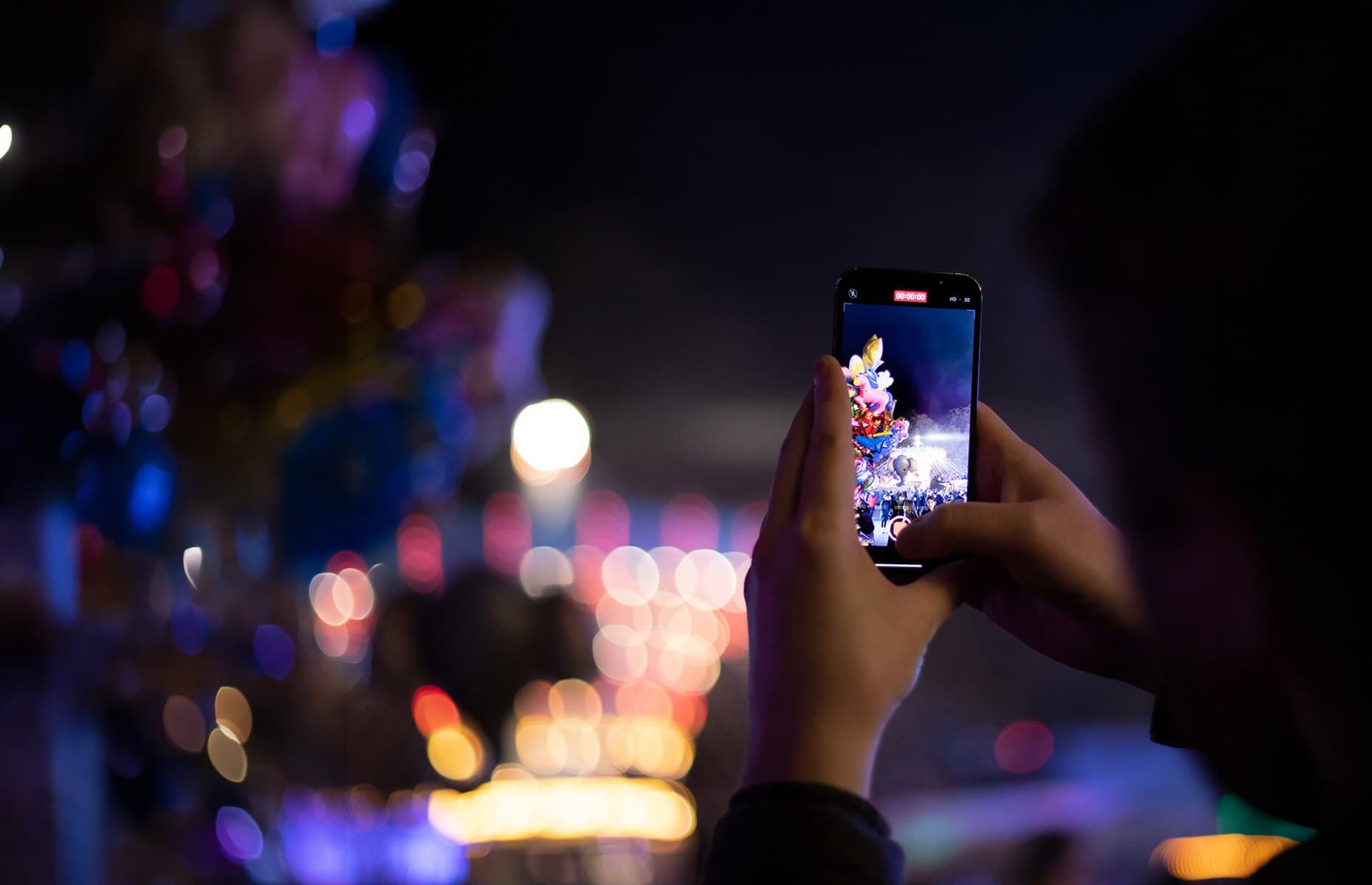 Ein Besucher filmt die nächtliche Bocholter Kirmes mit dem Smartphone
