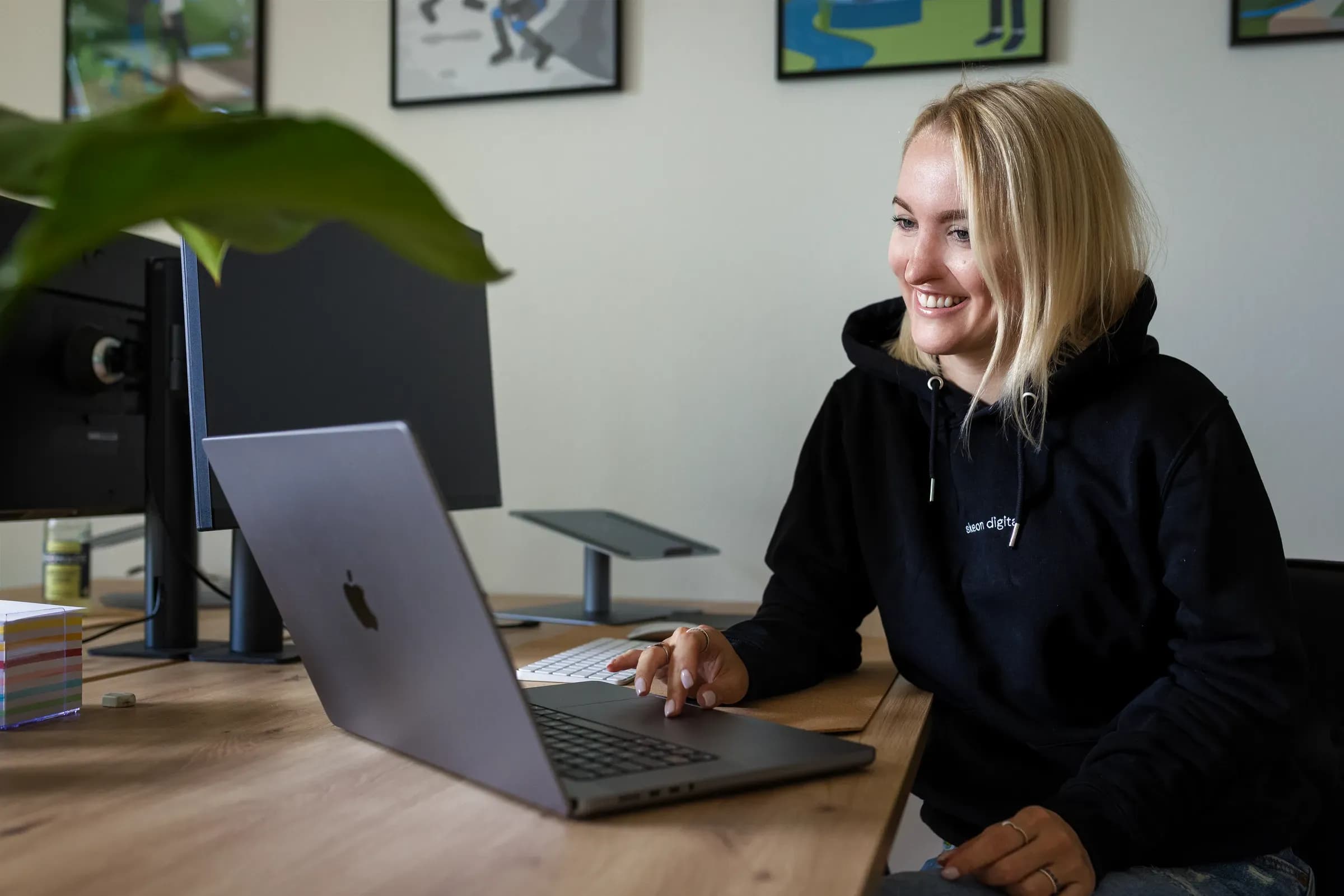 Kollegin von skeon digital lächelt beim Schreiben am Laptop