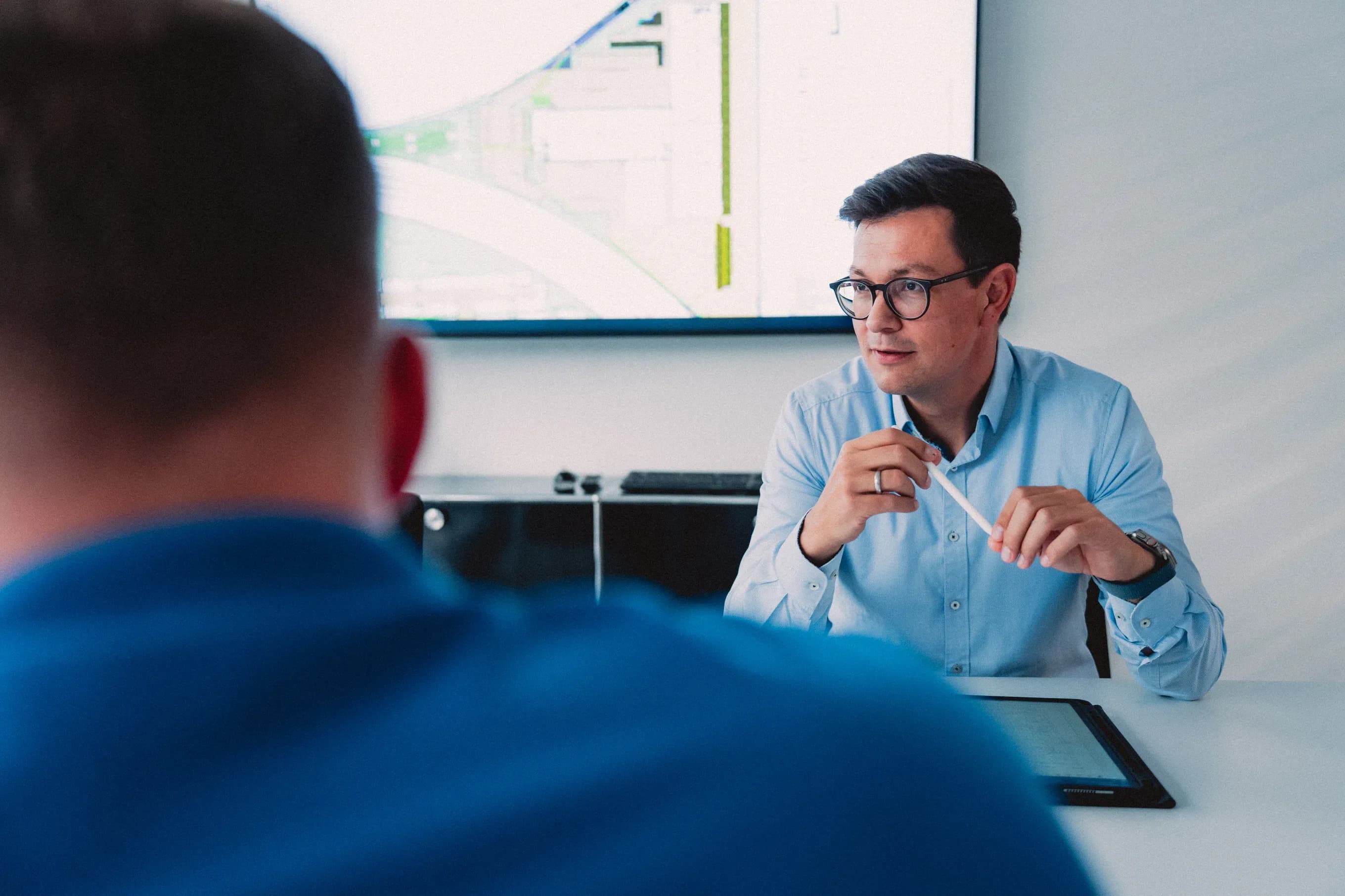 Besprechung bei Giesers Bau: ein Mitarbeiter erklärt vor einem Bauplan auf dem Bildschirm