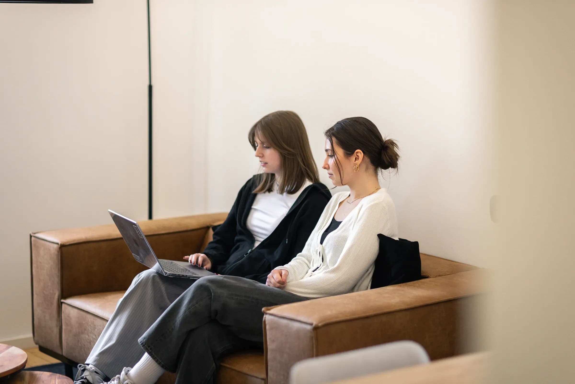 Zwei Kolleginnen von skeon digital mit Laptop auf dem Sofa im Büro