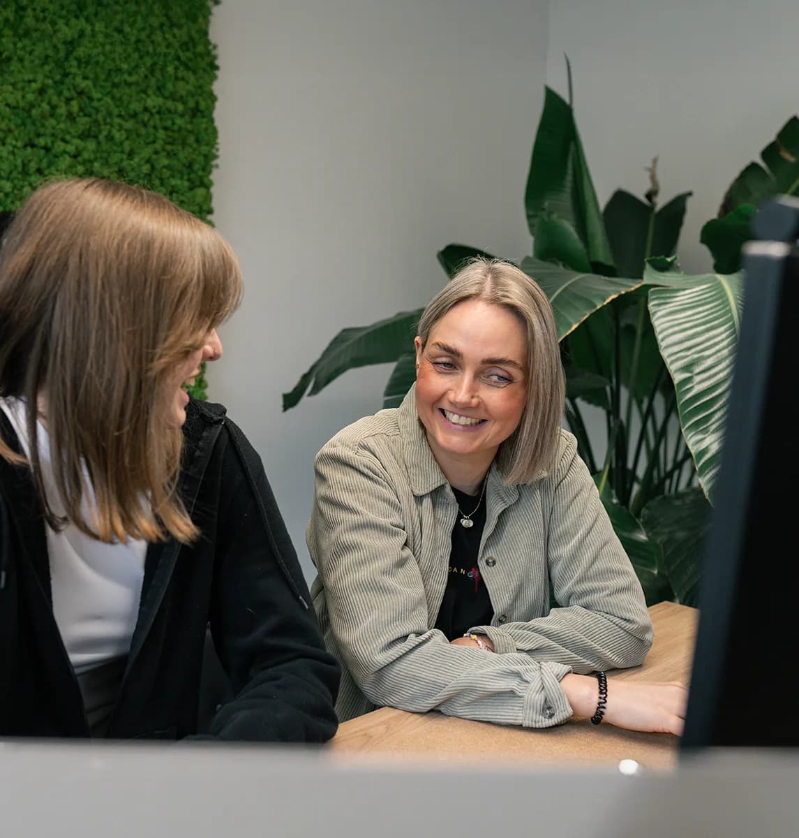 Zwei Teammitglieder von skeon digital lachen gemeinsam am Schreibtisch